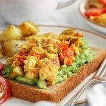 There are roasted potatoes, sliced cherry tomatoes as well as a slice of bread topped with mashed avocado and a silken tofu scramble.