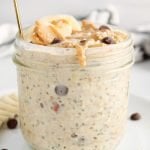 Front angle view on a jar filled with an high protein overnight oats topped with sliced bananas and a drizzle of peanut butter.