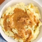 Overhead view on a small plate containing some vegan caramelized onion gravy with a spoon on the side and more black pepper on the side as well.