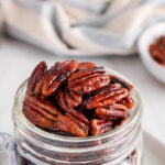 Close up on the top of a jar showing some vegan candied pecans.