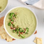 Overhead view on 2 bowls of vegan broccoli almond soup garnished with more roasted almonds and broccoli.