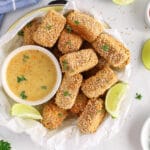 Overhead view on a bowl filled with baked panko tofu nuggets with a side of dijon mustard sauce and sprinkled with fresh parsley.