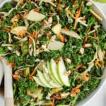 Overhead view on a large bowl filled with a kale crunch salad topped with sliced green apples and almonds.