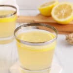 Overhead view on a short glass filled with a lemongrass ginger tea topped with a slice of lemon.