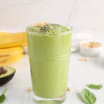 Front angle view on a healthy and vegan glass of avocado peanut butter green smoothie.