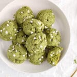 Overhead view on a few vegan matcha cookies piles on a plate with a glass of milk on the side.