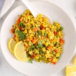 Overhead view on a bowl filled with a garlic turmeric fired rice loaded with peas, red pepper and carrots.
