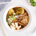 Overhead view on a bowl of vegan kimchi ramen filled with bok choy, tofu, shiitake and green onion.