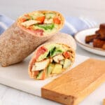 Showing is the inside of a vegan balsamic tofu wraps with more tofu soaking in a balsamic marinade in the background.