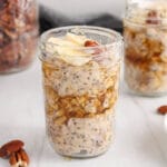 Showing is a small jar of maple pecan overnight oats topped with maple syrup and bananas.