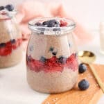 Front angle view on a small jar of flaxseed pudding layered with strawberry jam and fresh blueberries.