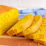 There are a few slices of vegan sandwich turmeric bread on a wooden board.