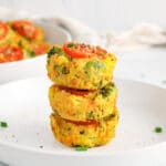There are 3 vegan egg muffins piled over each other on a plate with some chives around.
