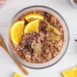Overhead view on a bowl of chocolate orange overnight oat topped with sliced orange, chia seeds and cacao nibs.