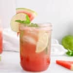Front view on a glass of watermelon mint mojito mocktail with some fresh fruits in the background.