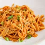 Front angle view on a bowl of gochujang pasta topped with green onion and black pepper.