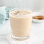 Front angle view on a short glass of creamy oat milk smoothie garnished with some chia seeds.