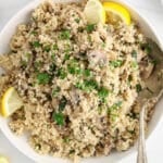 Overhead view on a large serving bowl filled with a mushroom couscous topped with fresh parsley.