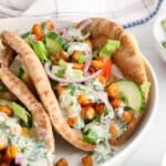 View on a vegan chickpea gyro filled with red onion, cucumber, tomatoes and a dairy-free tzatziki sauce.