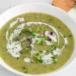 Angle view on a bowl of vegan zucchini potato soup topped with a vegan cream and chives.