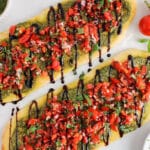Overhead view on 2 vegan flatbread bruschetta made with pesto.