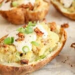 Close up on a vegan twice baked potatoes topped with tofu sour cream and green onions.