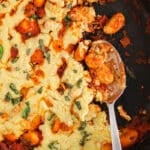 View on a gnocchi marinara in a cast iron pan with a large spoon showing the gnocchi.