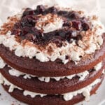 Showing a vegan black forest cake with shredded chocolate in the background.