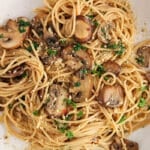Close up on a bowl of spaghetti mushroom aglio olio topped with vegan parmesan.