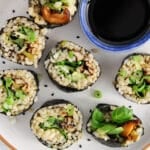 Overhead view on a plate with a few vegan shiitake sushi rolls and a small bowl of soy sauce.