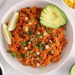 Overhead view on a vegan Mexican rice topped with cilantro and green onion with a side of avocado.