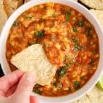 Overhead view on a tortilla chip dipping in a homemade mango habanero salsa.