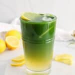 View on a tall glass of Iced Matcha Latte with lemon slices and ice cubes.