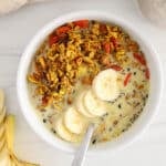 View on a cereal bowl made with a superfood turmeric granola with plant milk and sliced bananas.