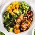 View on a baked tofu teriyaki buddha bowl also made with broccoli, shiitake mushrooms, pineapple and edamame.