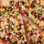 Over head view on a hand taking a slice of vegan BBQ jackfruit pizza.