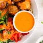 Close up on a side harissa vinaigrette in a buddha bowl.
