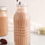 View on a creamy vegan hemp chocolate milk in a glass with black and white straws.