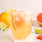 Showing a glass of bubbly grapefruit mocktail with slices of grapefruit.