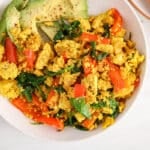 Close up on a plate with a curry tofu scramble and a side of avocado and toasts.