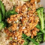 Close up on a sticky tempeh over rice with green vegetables.