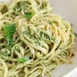 Focus on the pesto sauce over a bowl of pasta (linguini).