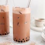 View on a tall glass of chocolate milk tea filled with ice cubes with dark tapioca pearls at the bottom.