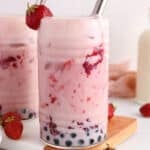 View on a glass of strawberry bubble tea with some strawberries around.