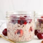 Front view on a jar filled with a cherry overnight oats recipe that's garnished with more fresh cherries.