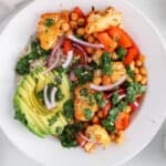 View on a chimichurri bowl made out of brown rice, roasted cauliflower and red pepper and spiced chickpeas.