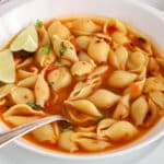 There is a spoon in a bowl of Mexican shell soup.