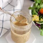 View on a creamy vegan basil balsamic vinaigrette in a jar with a spoon taking some of it.