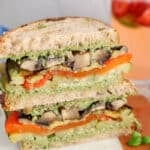 Showing a sandwich made with vegan pesto and layered with roasted vegetables.