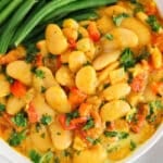 Close up on a creamy curry sauce made with large butter bean and serve with green beans.